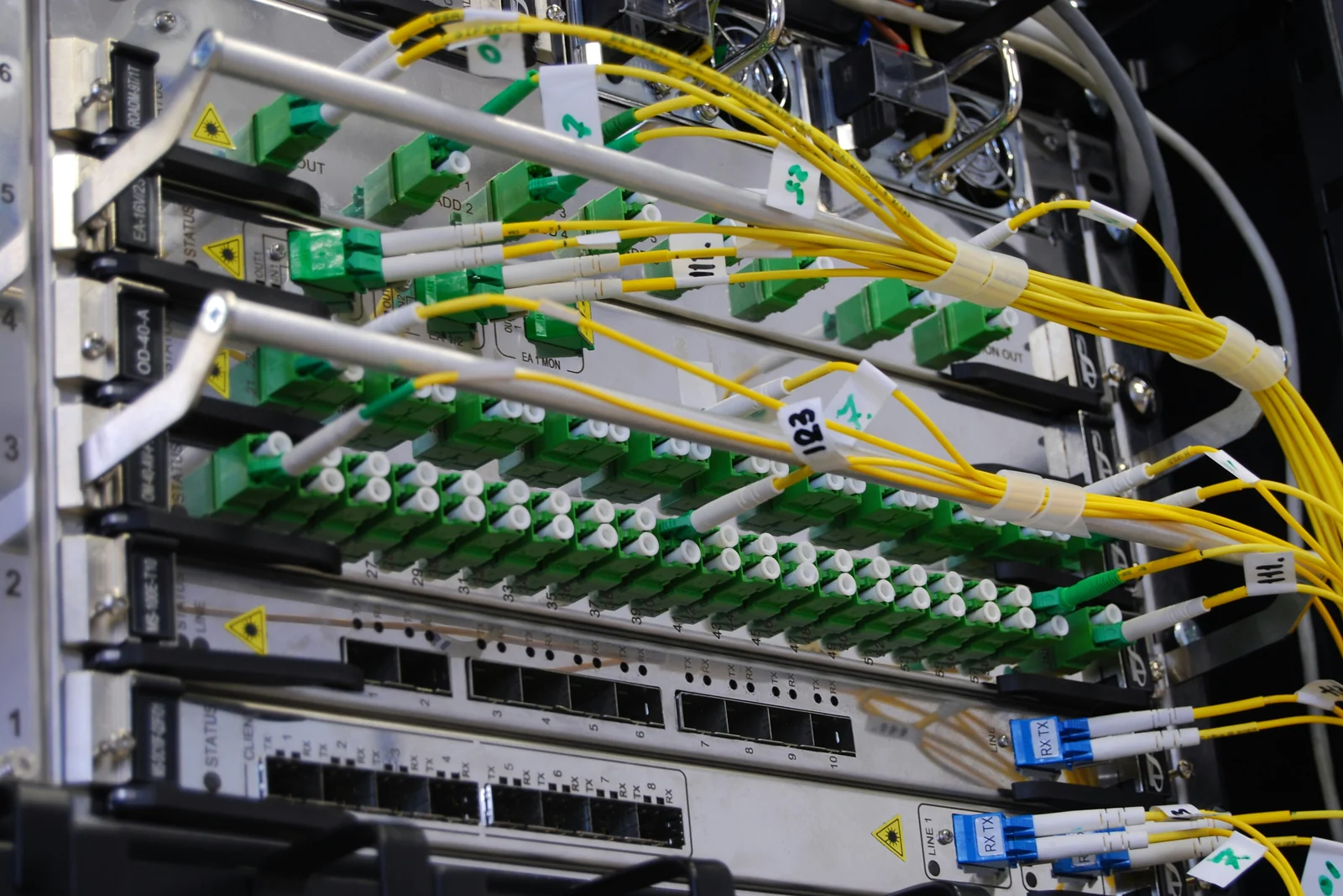 A fiber optic patch panel with green ports and bundled yellow cables