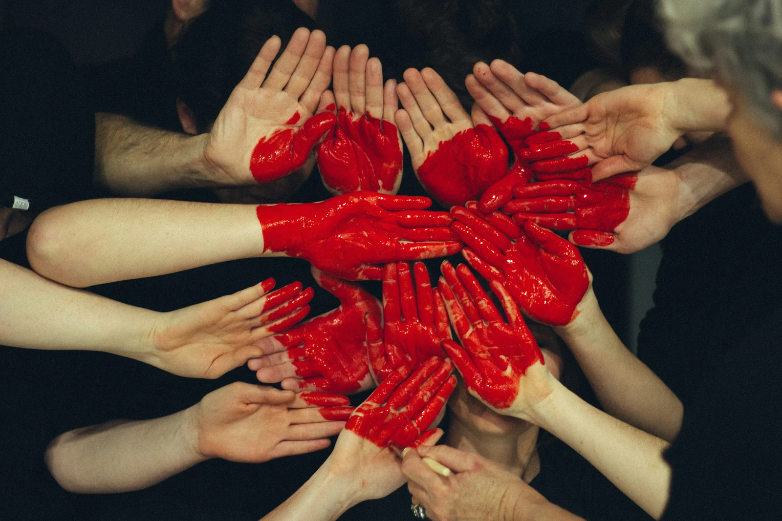Many hands painted red pressed together to form a heart