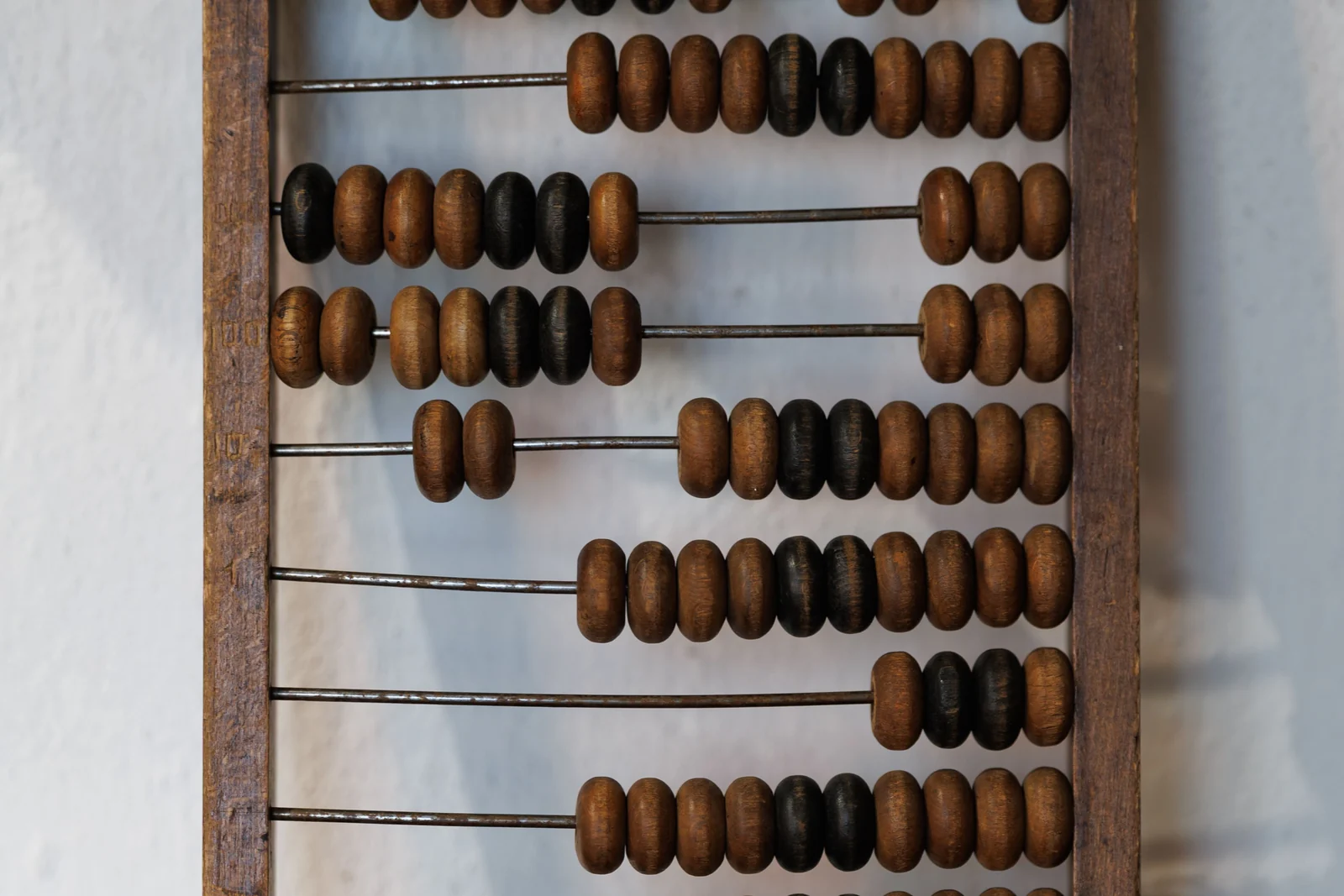 An antique wooden abacus, worn beads counted across its rows