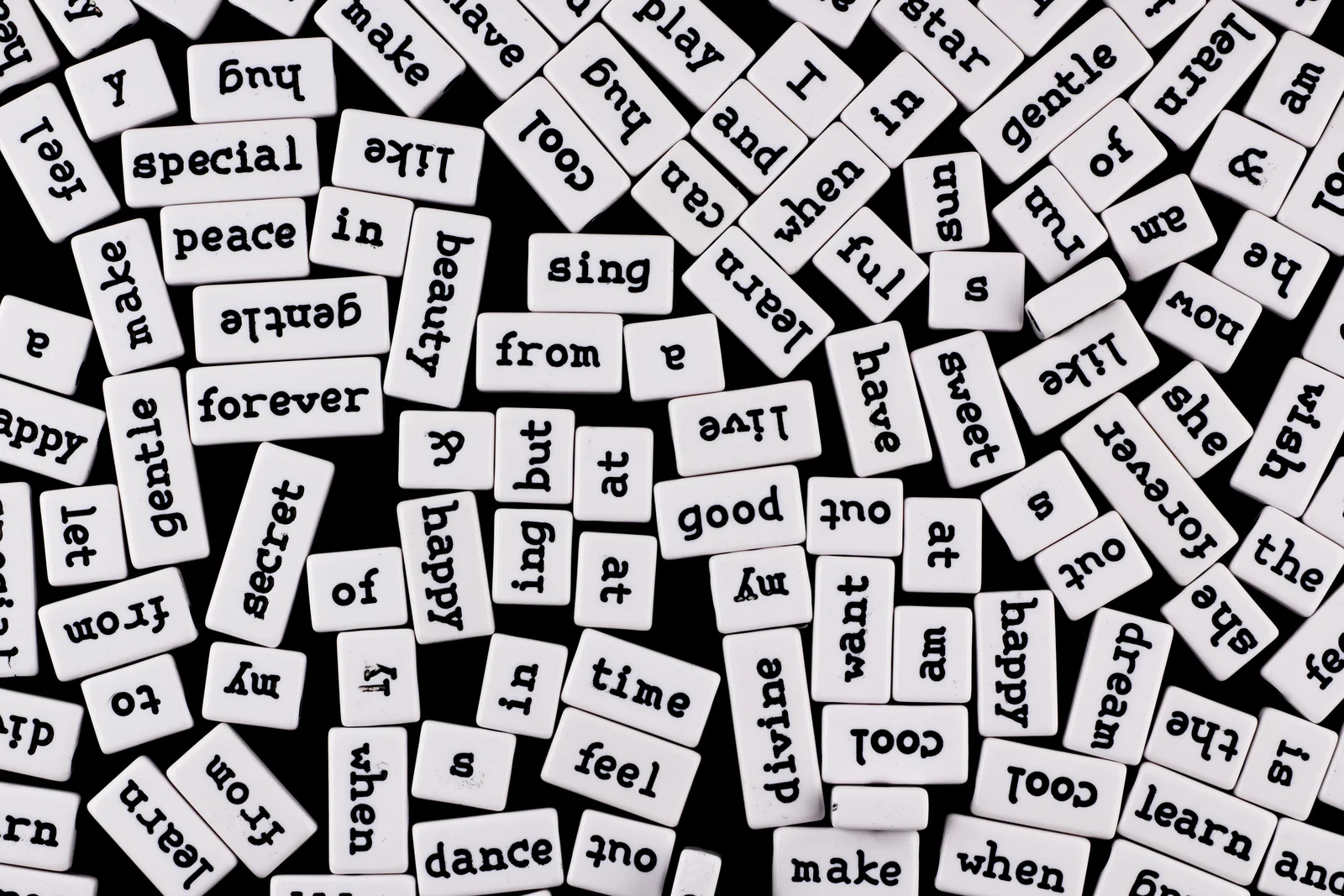A scatter of white word tiles with black typewriter letters on a dark surface