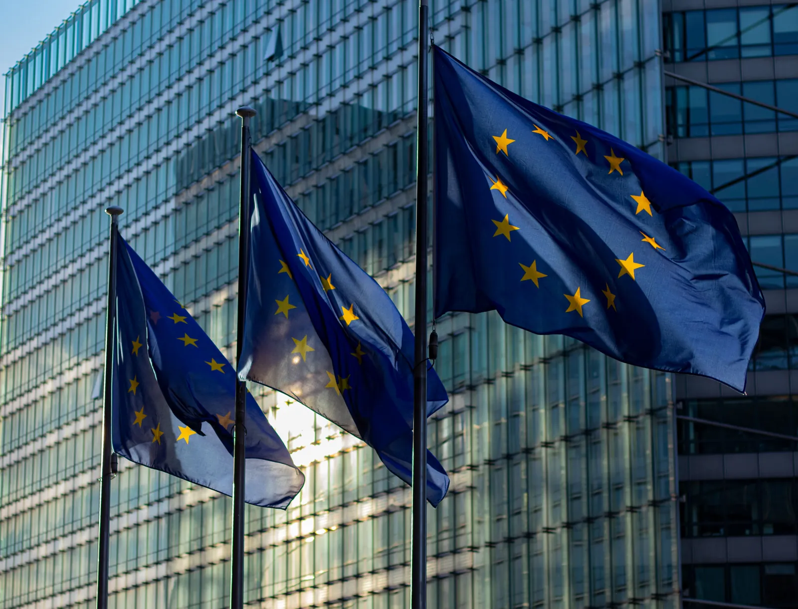 European Union flags in front of a glass office building, representing GDPR rules for digital advertising and measurement