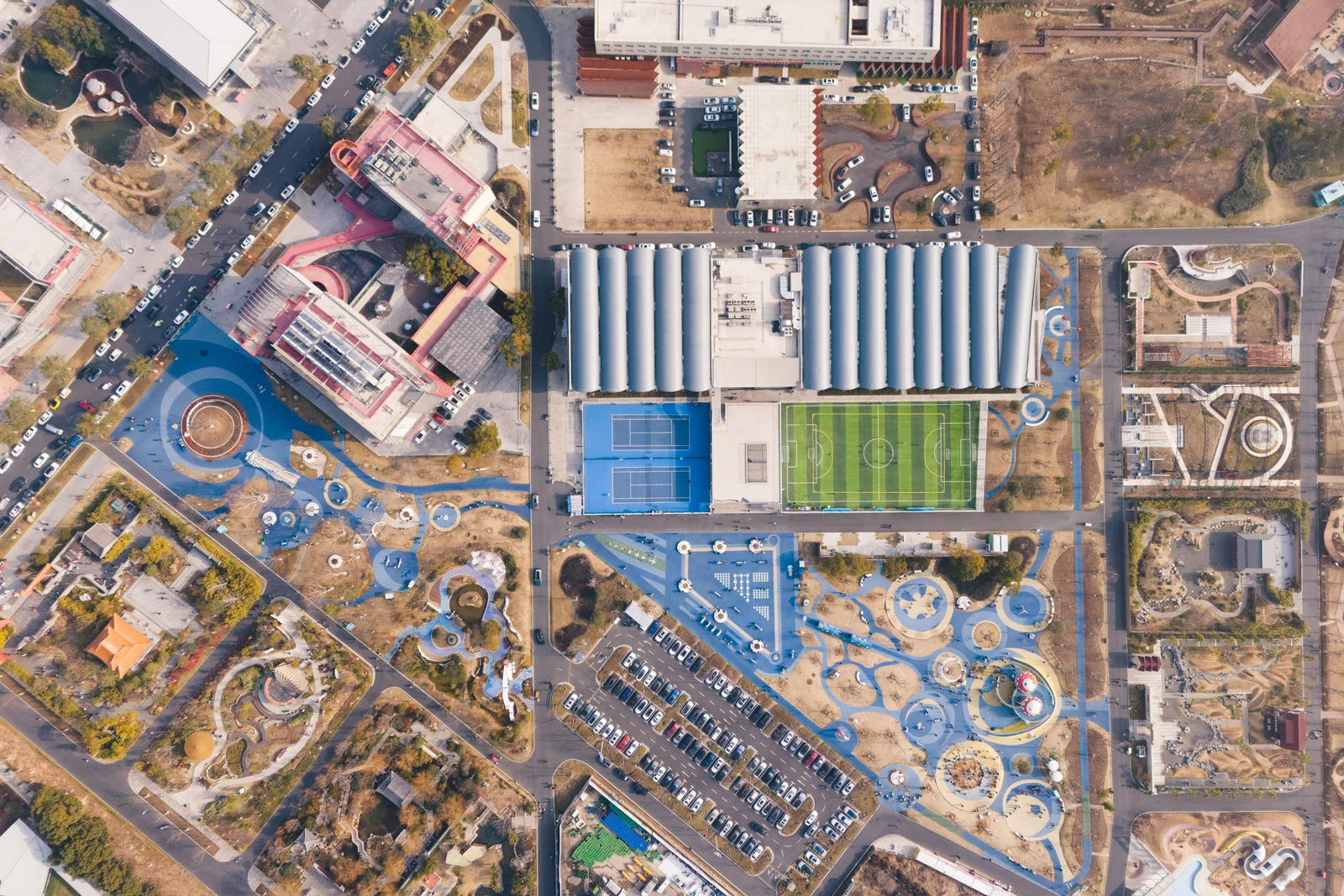 An overhead aerial grid of a planned district: sports fields, parking lots, buildings, and green space