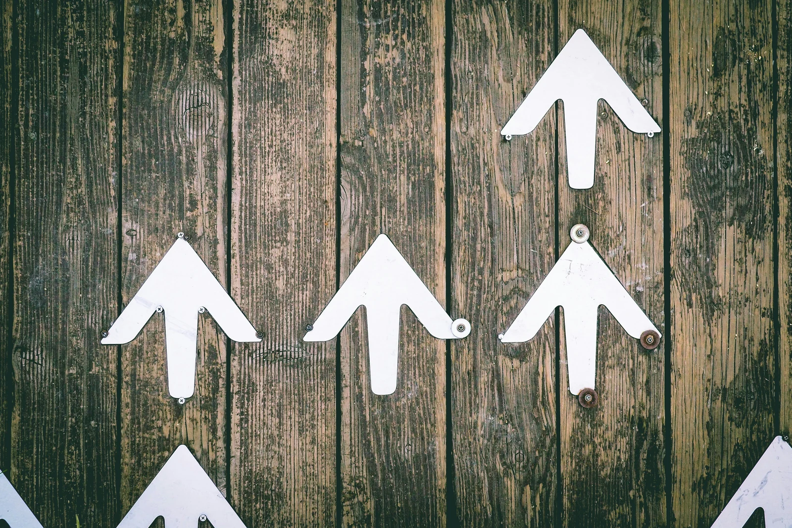 White arrows pointing up on weathered wood, the direction PPC results take with time