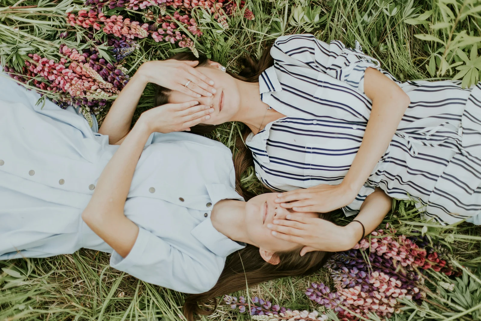 Two nearly identical women lying in wildflowers, a lookalike audience of two