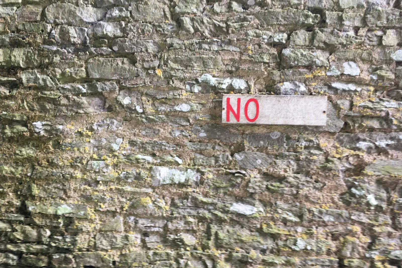 A weathered NO sign on a stone wall, the spirit of negative keywords