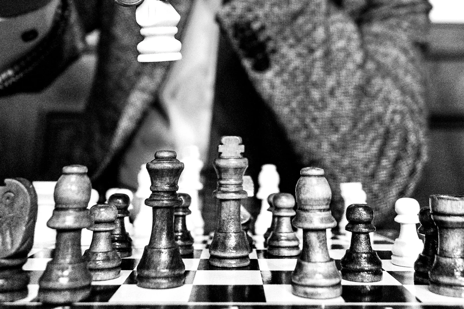 Ranks of chess pieces across the board in close focus, black and white