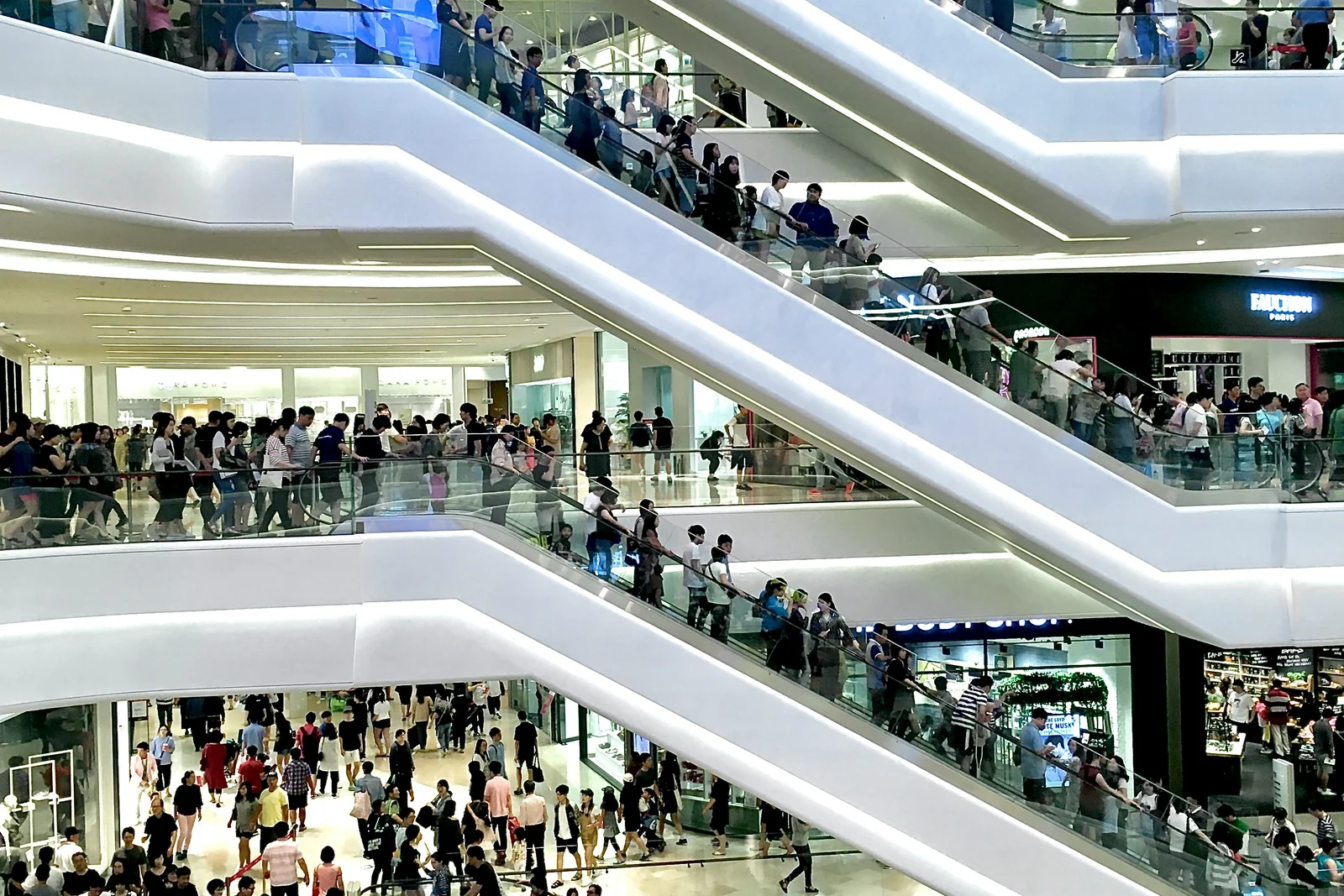 Layers of crowded escalators crisscrossing a shopping mall atrium