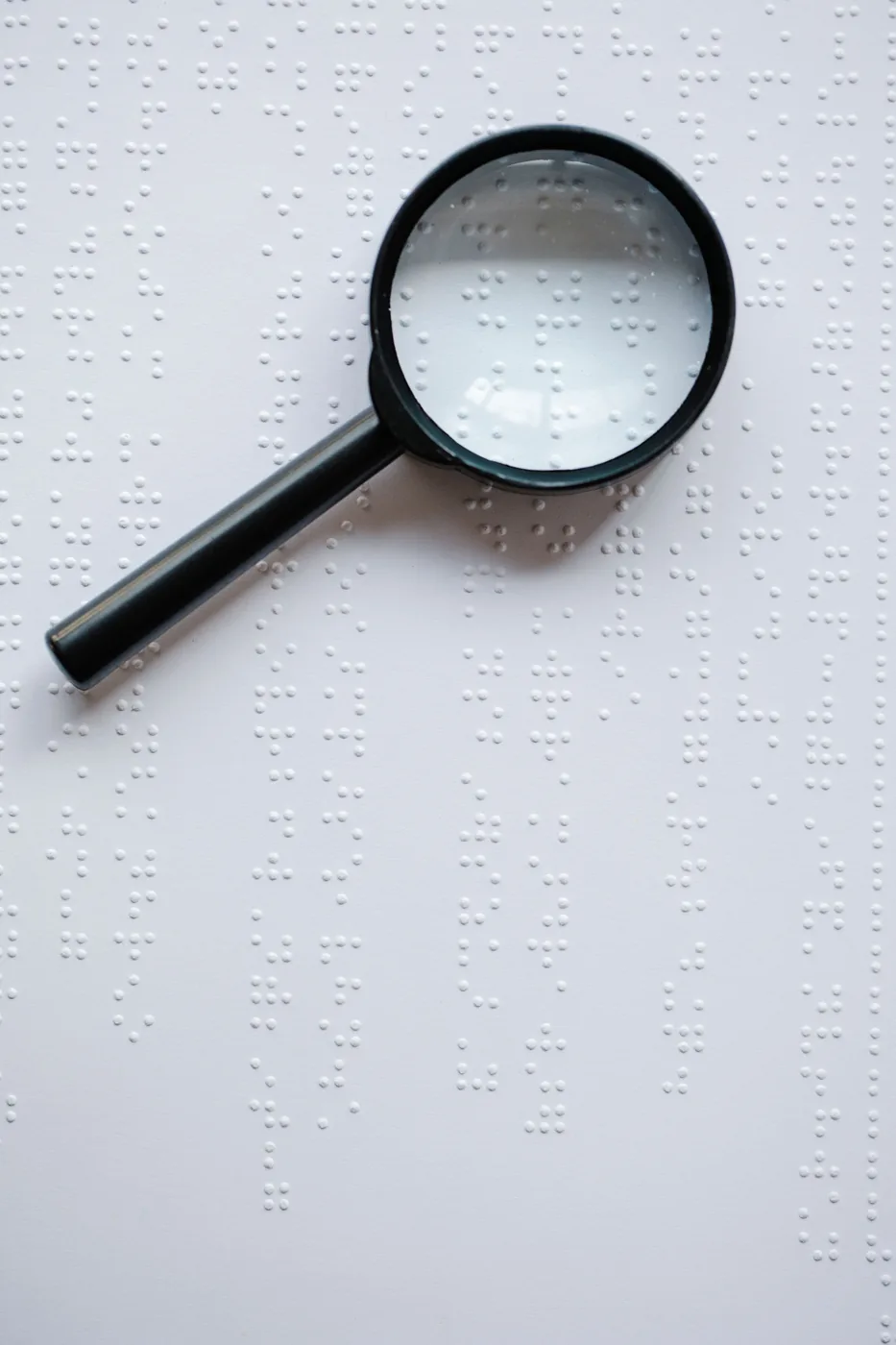 Magnifying glass over braille text, representing the structured data layer machines read