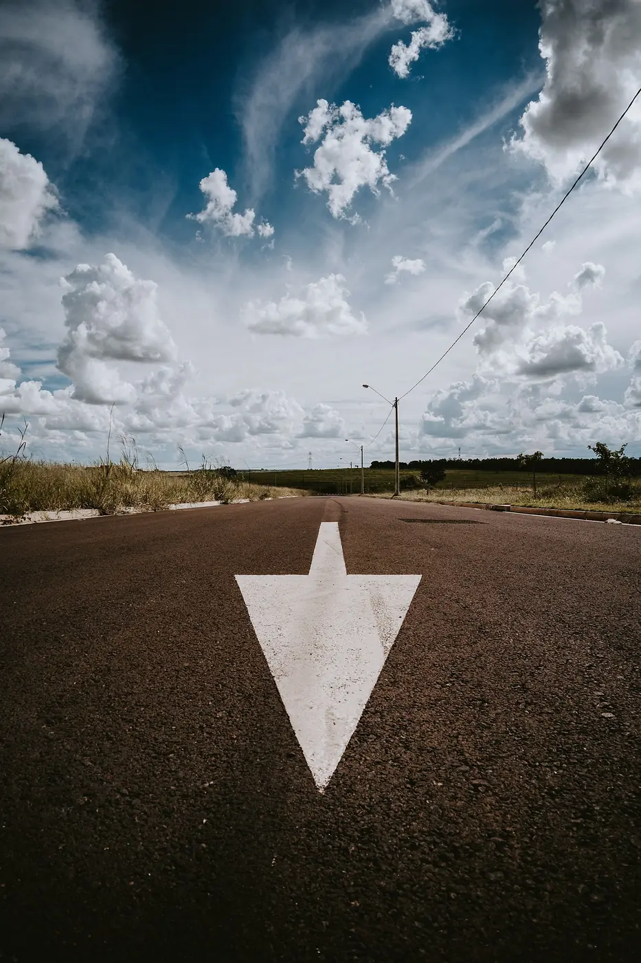 White arrow painted on pavement pointing downward, representing a declining metric