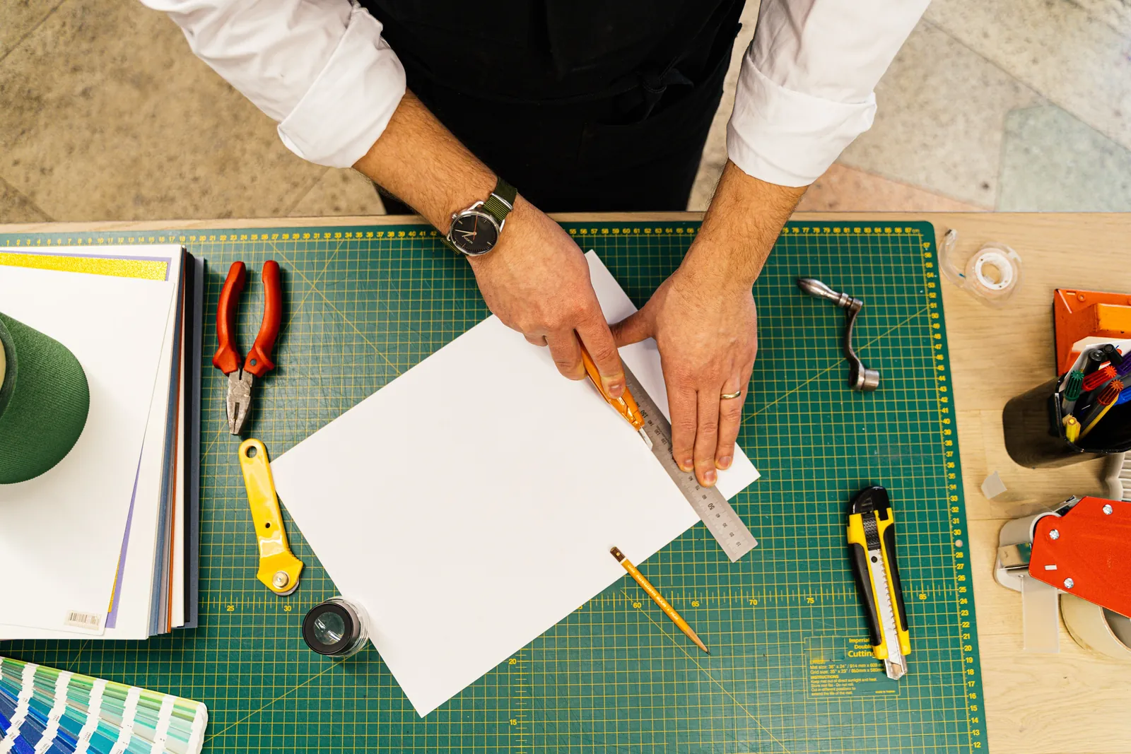 Hands measuring and trimming a sheet on a cutting mat, representing a Q2 media plan being recut mid-quarter