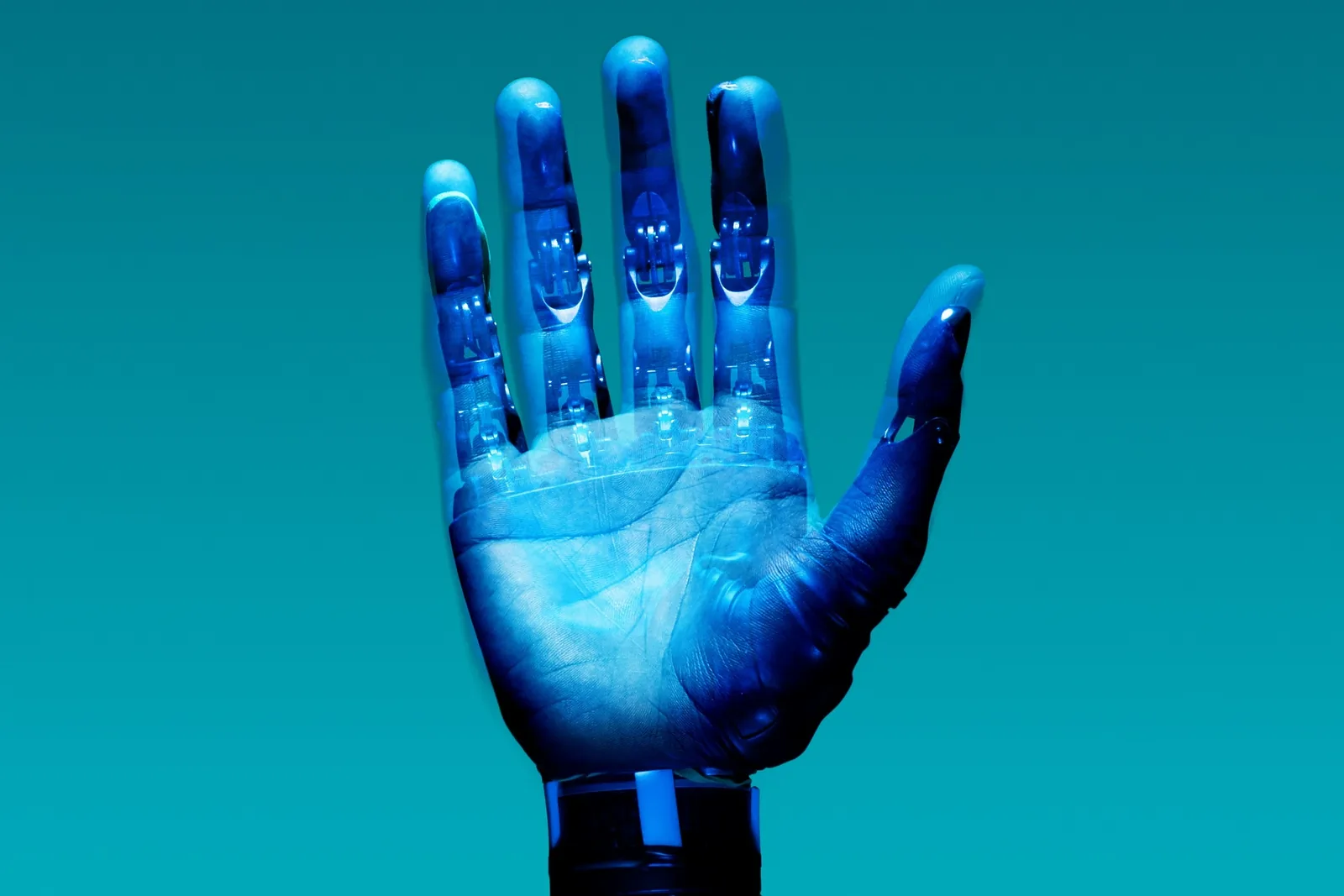 A transparent prosthetic hand raised against a teal background with its mechanics visible: AI tools and automation built for marketing and communications teams