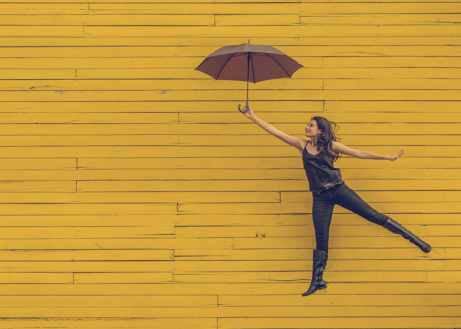 A woman leaping with an open umbrella in front of a painted wooden wall: digital strategy, with media planning tied to contribution margin, MER, payback, and retention